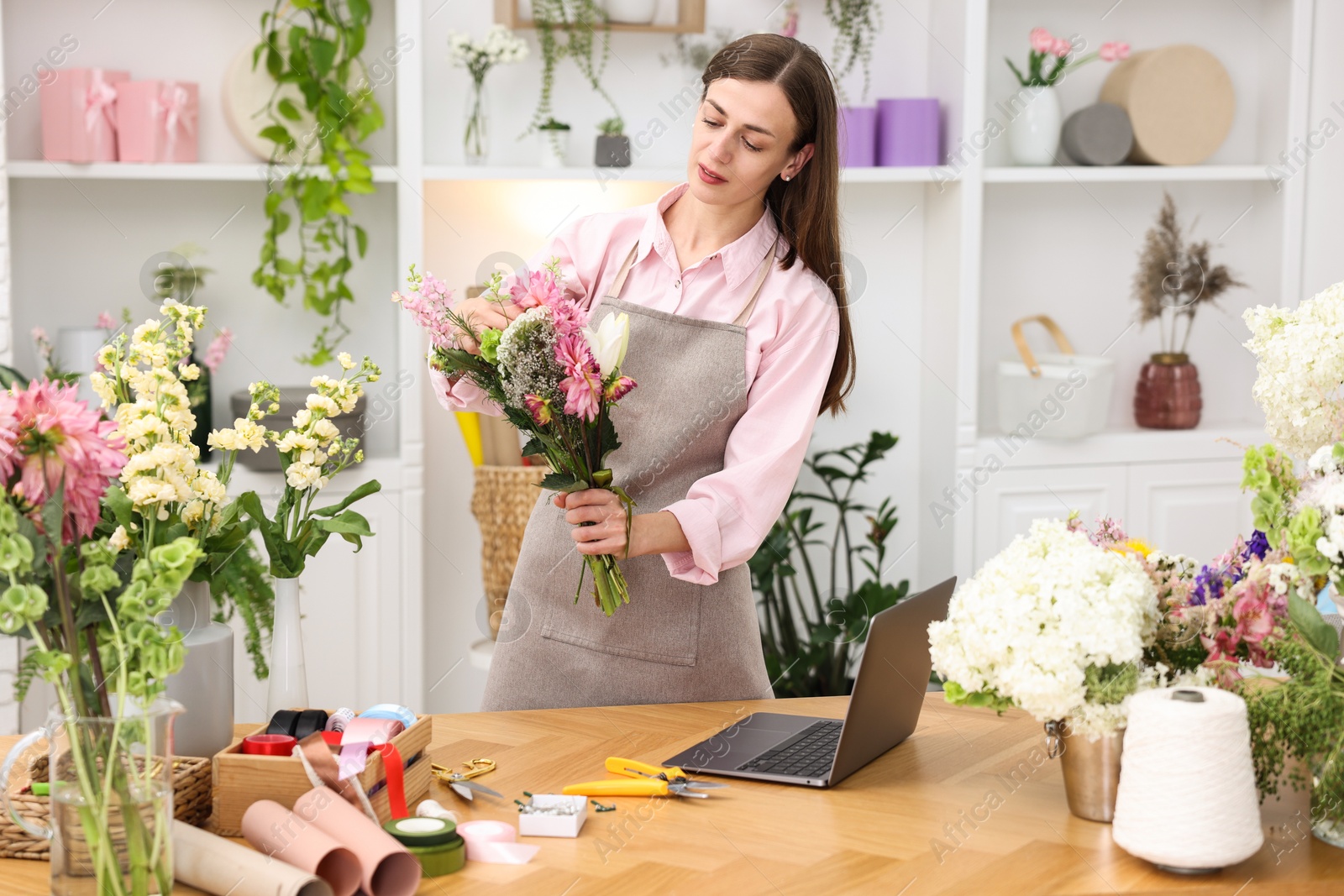 Professional florist making bouquet of flowers at wooden table in shop Photo of Professional florist making bouquet of flowers at wooden table in shop