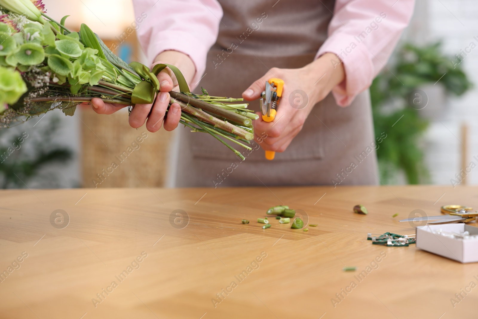 Professional florist making bouquet of flowers at wooden table in shop, closeup Photo of Professional florist making bouquet of flowers at wooden table in shop, closeup