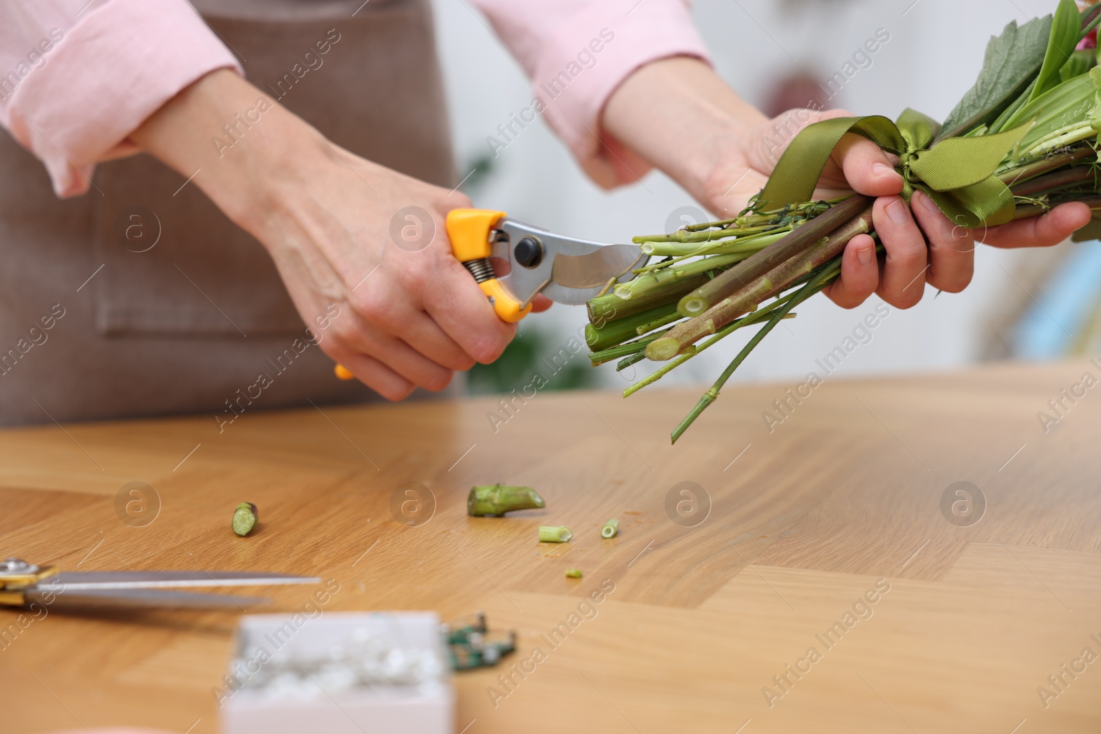 Professional florist making bouquet of flowers at wooden table in shop, closeup Photo of Professional florist making bouquet of flowers at wooden table in shop, closeup