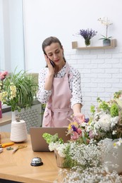 Photo of Professional florist talking on smartphone while working in shop