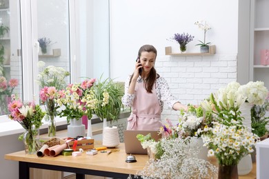 Photo of Professional florist talking on smartphone while working in shop