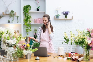 Photo of Professional florist talking on smartphone while working in shop