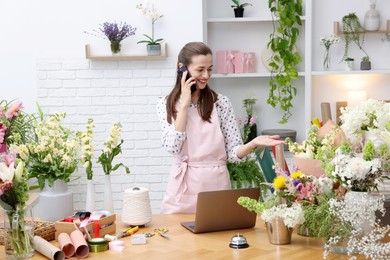 Photo of Professional florist talking on smartphone while working in shop