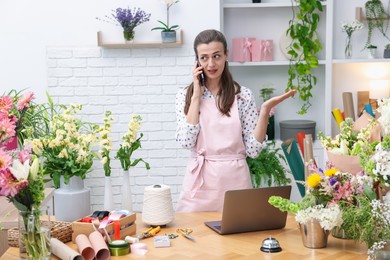 Photo of Professional florist talking on smartphone while working in shop