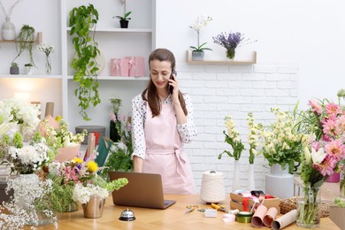 Photo of Professional florist talking on smartphone while working in shop