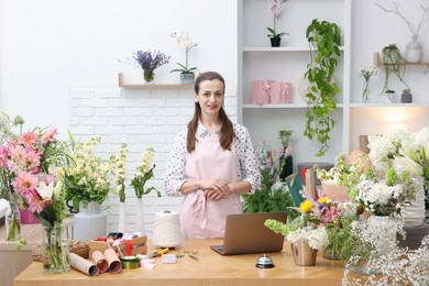 Photo of Professional florist working at wooden table in shop