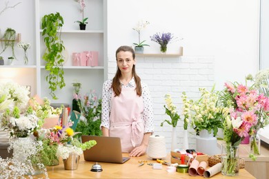 Photo of Professional florist working at wooden table in shop