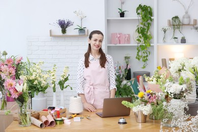 Photo of Professional florist working at wooden table in shop