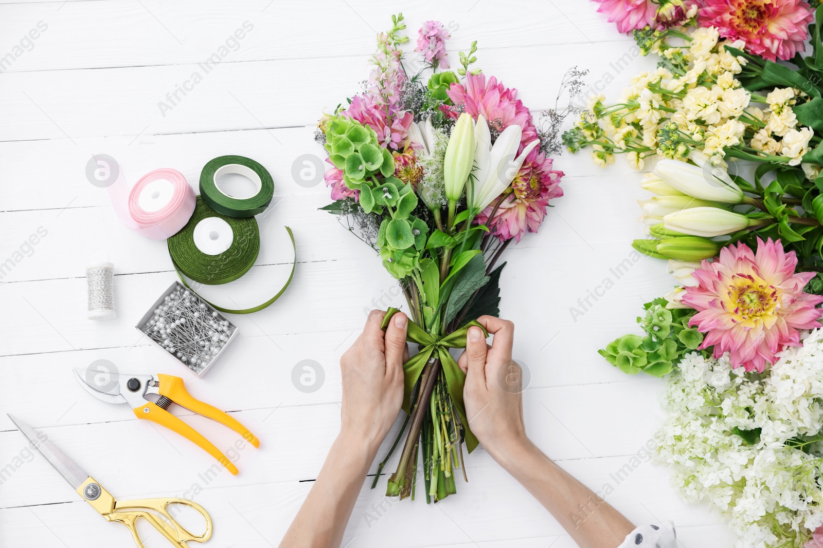 Florist making bouquet of flowers at white wooden table, top view Photo of Florist making bouquet of flowers at white wooden table, top view