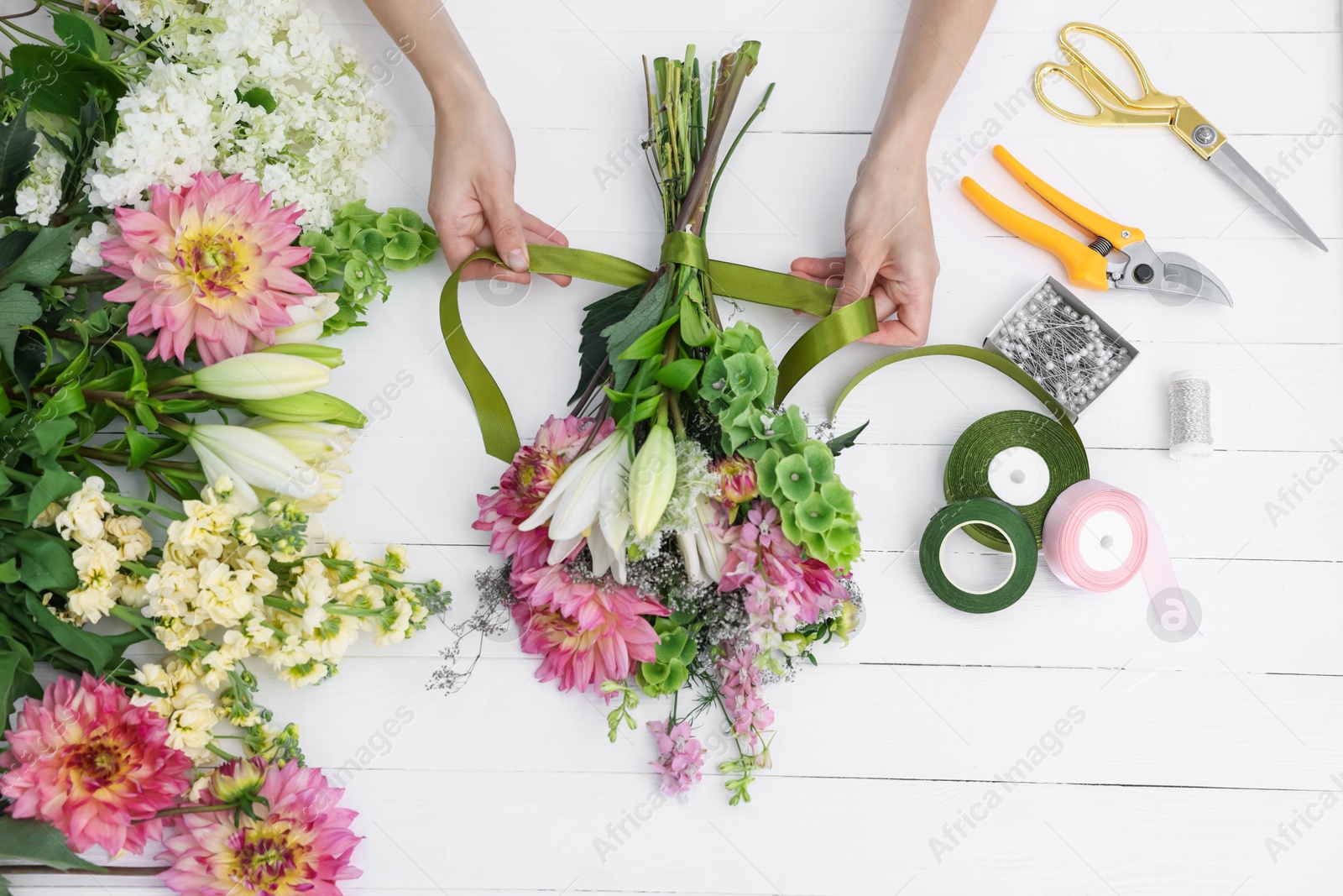 Florist making bouquet of flowers at white wooden table, top view Photo of Florist making bouquet of flowers at white wooden table, top view