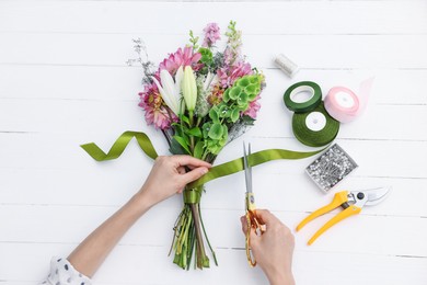 Photo of Florist making bouquet of flowers at white wooden table, top view