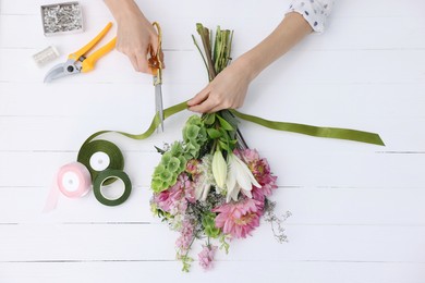 Photo of Florist making bouquet of flowers at white wooden table, top view
