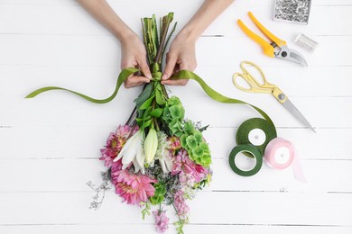 Photo of Florist making bouquet of flowers at white wooden table, top view