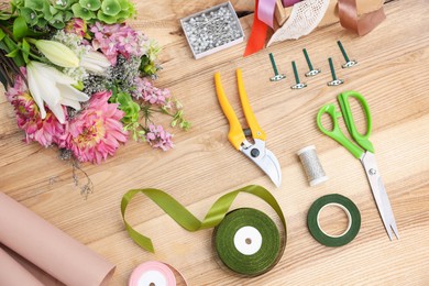 Photo of Florist. Bouquet of flowers, secateurs, scissors and ribbons on wooden table, top view