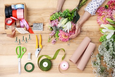 Photo of Florist making bouquet of flowers at wooden table, top view