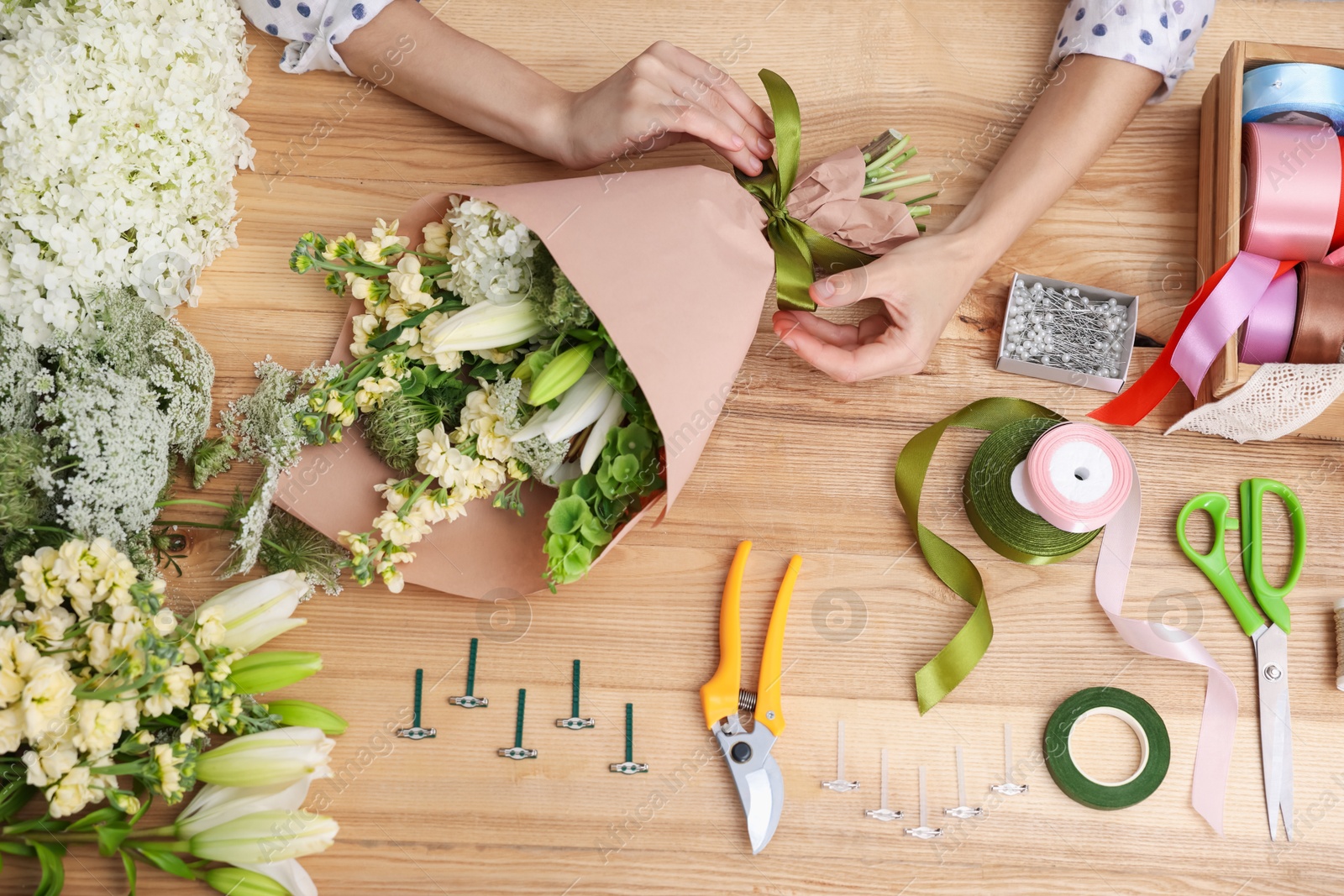 Florist making bouquet of flowers at wooden table, top view Photo of Florist making bouquet of flowers at wooden table, top view