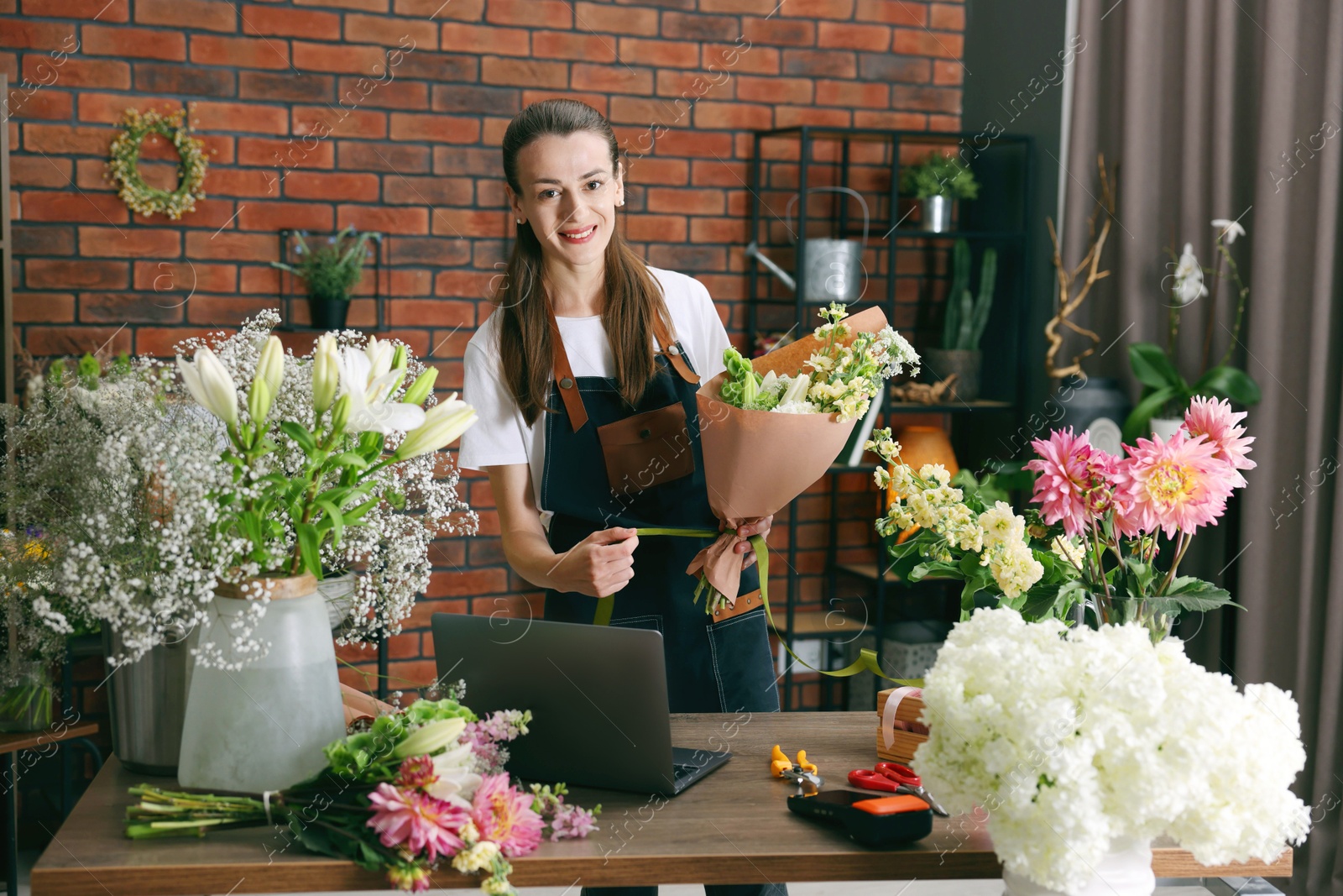 Professional florist making bouquet of flowers at wooden table in shop Photo of Professional florist making bouquet of flowers at wooden table in shop