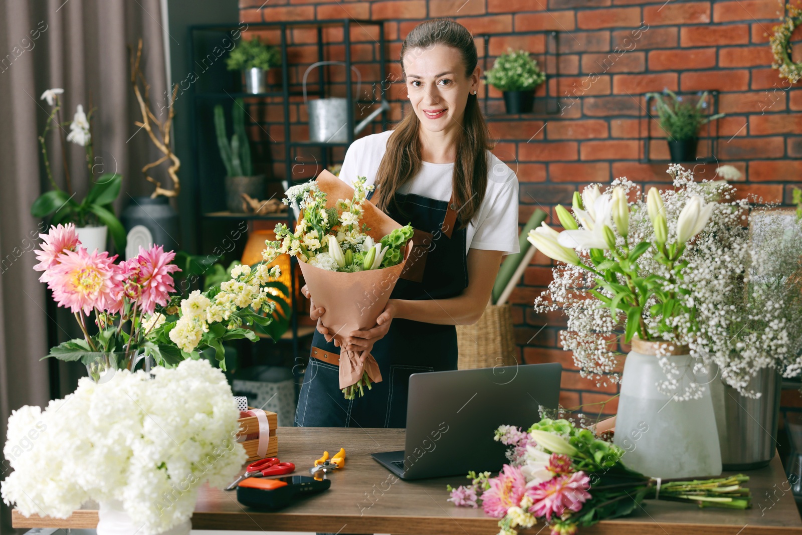 Professional florist making bouquet of flowers at wooden table in shop Photo of Professional florist making bouquet of flowers at wooden table in shop