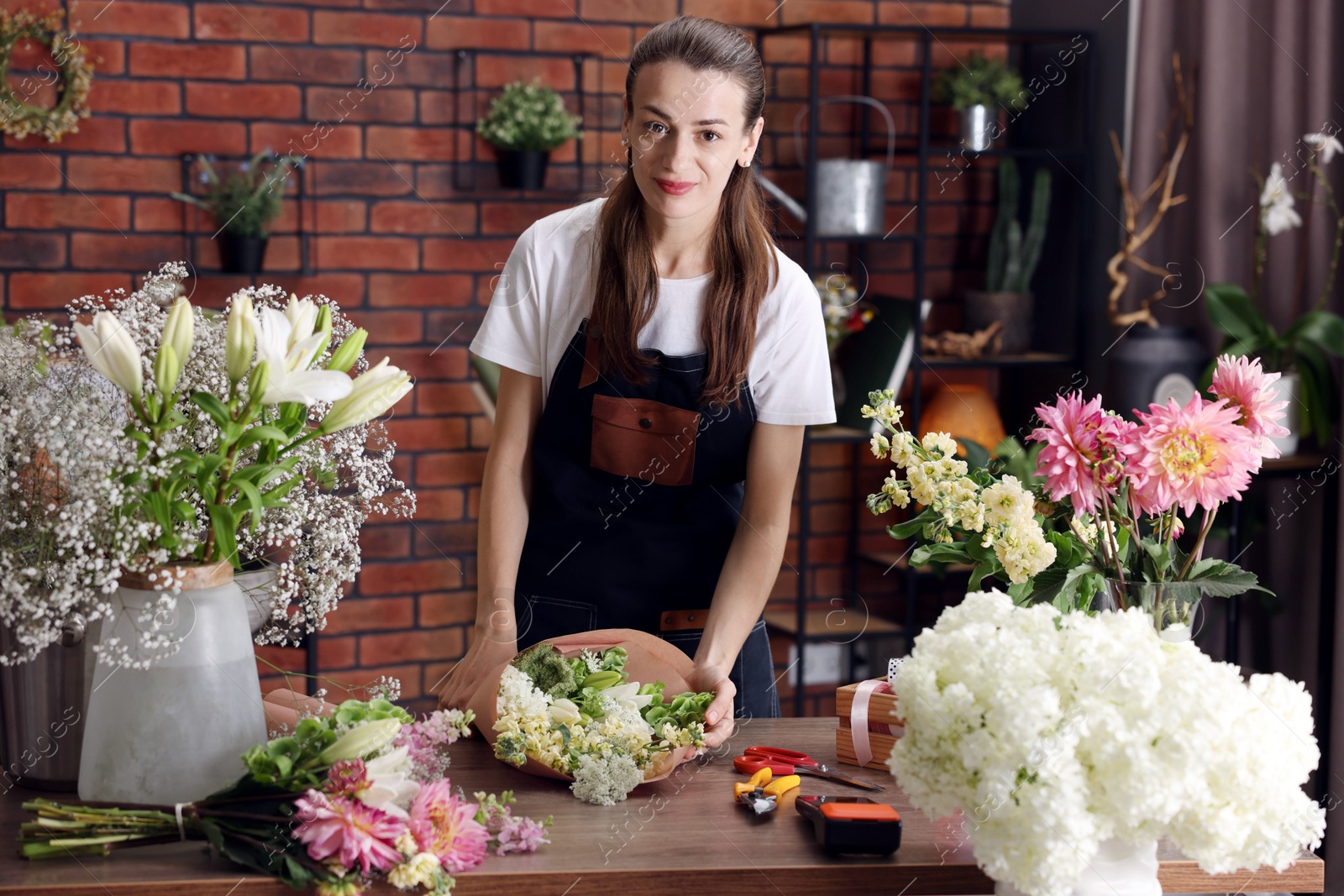 Professional florist making bouquet of flowers at wooden table in shop Photo of Professional florist making bouquet of flowers at wooden table in shop