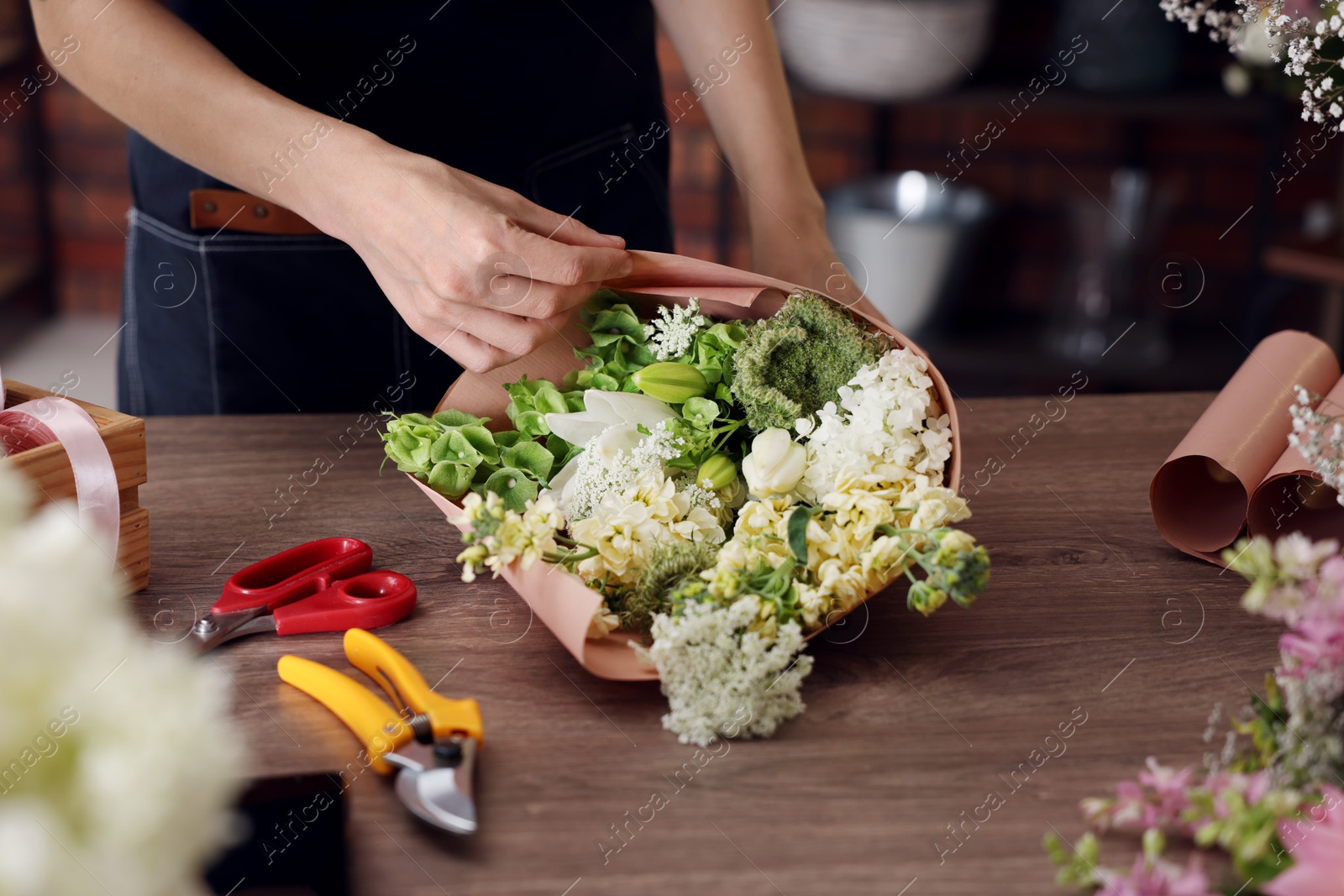 Photo of Professional florist making bouquet of flowers in shop, closeup