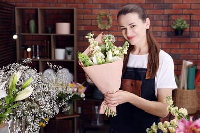 Photo of Professional florist with bouquet of flowers in shop