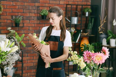 Photo of Professional florist with bouquet of flowers in shop