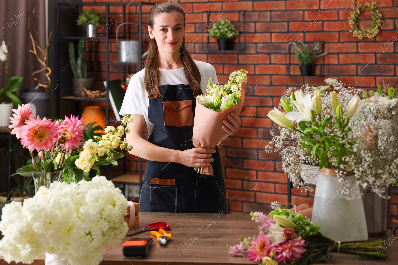 Professional florist making bouquet of flowers at wooden table in shop Photo of Professional florist making bouquet of flowers at wooden table in shop