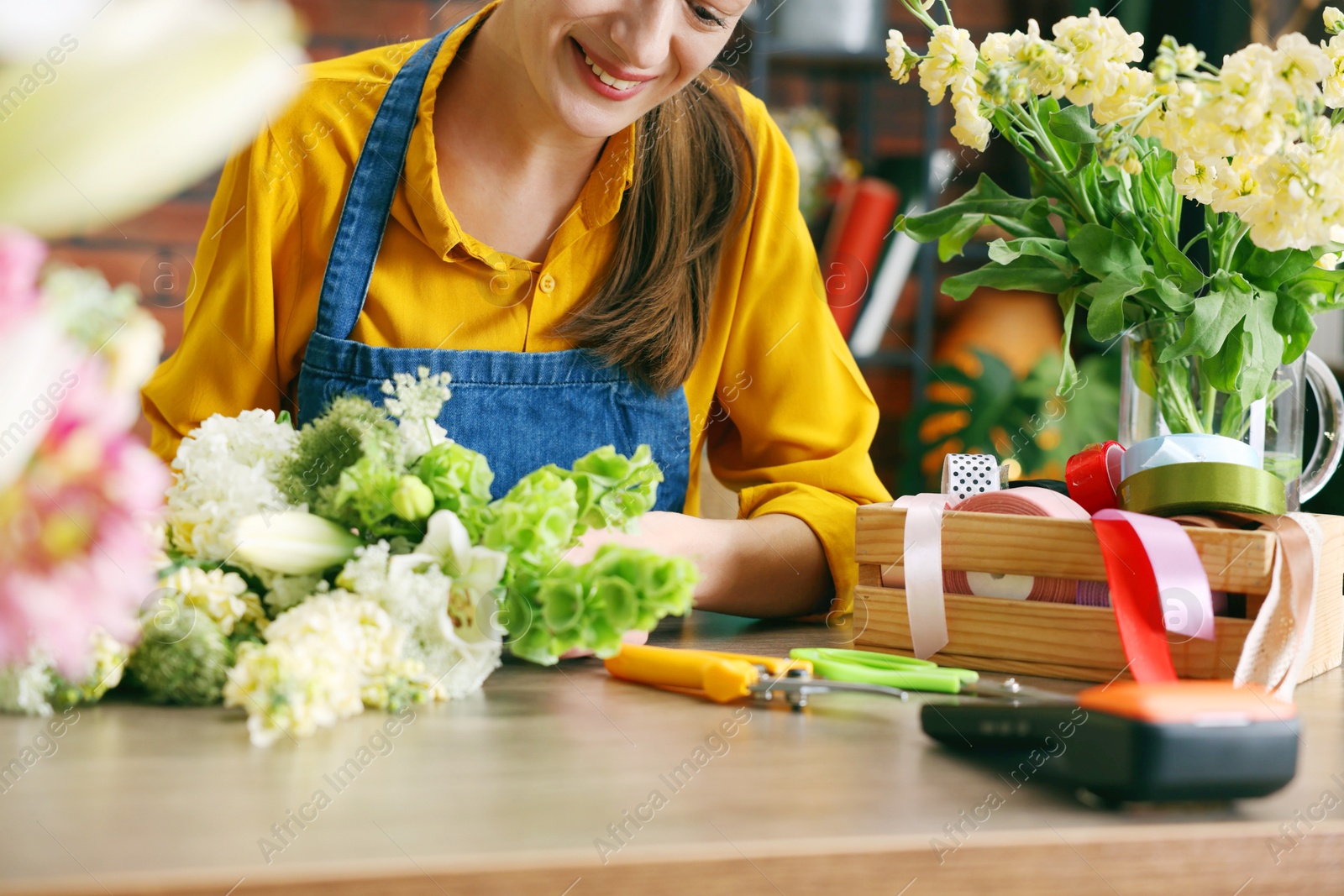 Professional florist making bouquet of flowers at wooden table in shop, closeup Photo of Professional florist making bouquet of flowers at wooden table in shop, closeup