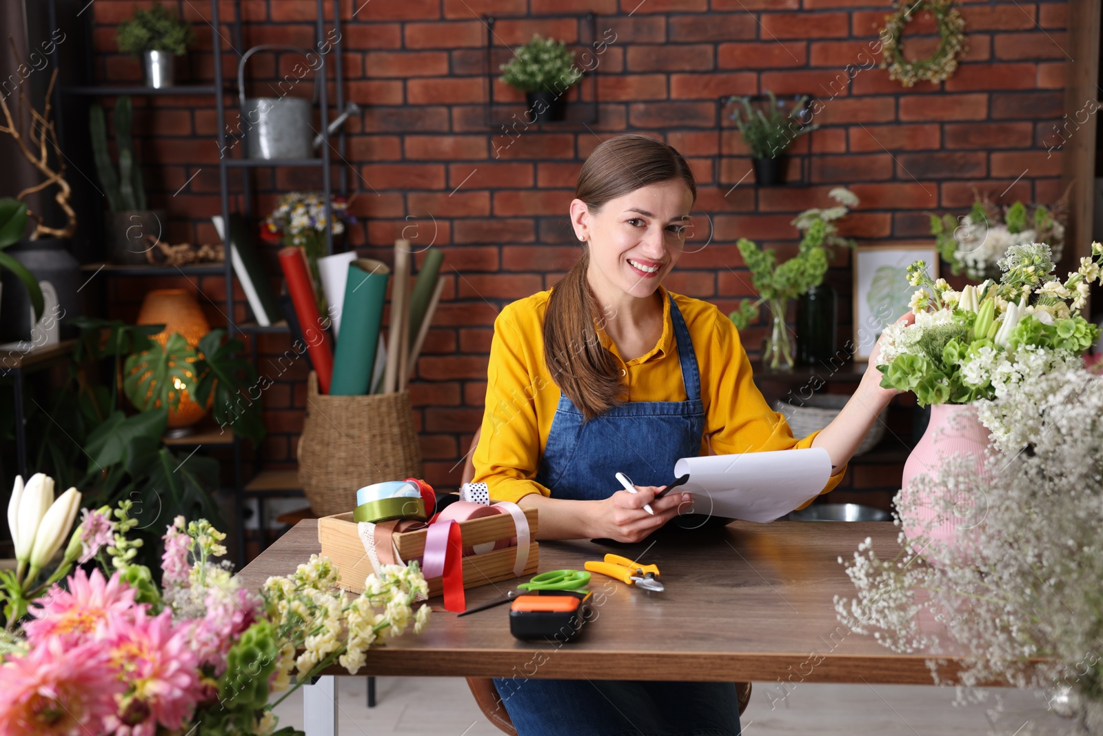 Photo of Professional florist working at wooden table in shop