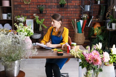 Photo of Professional florist working at wooden table in shop
