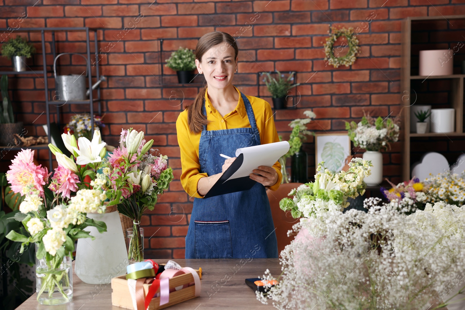Photo of Professional florist working at wooden table in shop