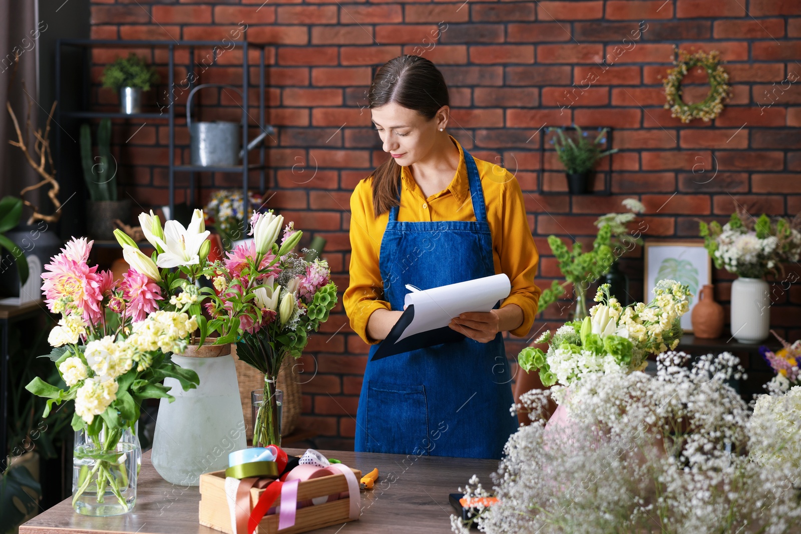 Photo of Professional florist working at wooden table in shop