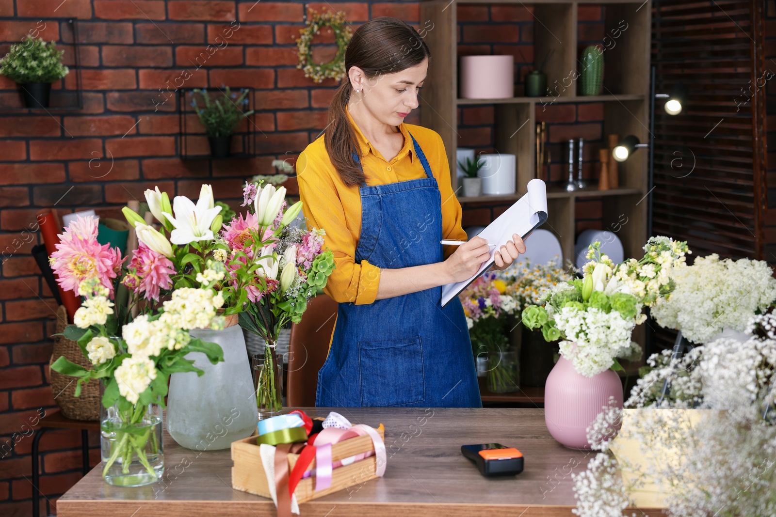 Photo of Professional florist working at wooden table in shop