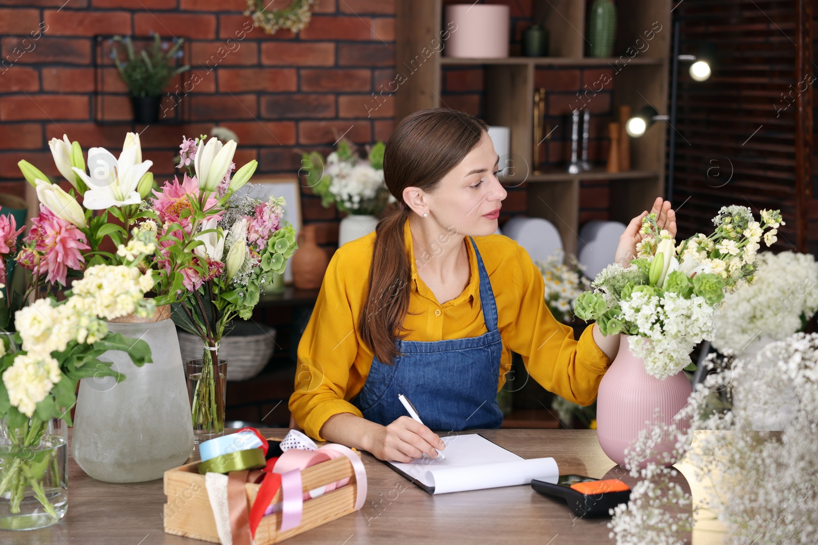 Photo of Professional florist working at wooden table in shop