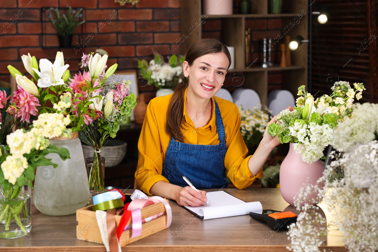 Photo of Professional florist working at wooden table in shop