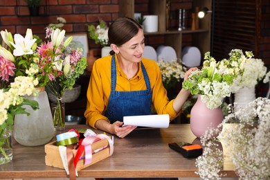 Photo of Professional florist working at wooden table in shop