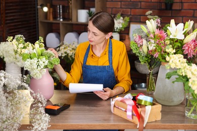 Photo of Professional florist working at wooden table in shop
