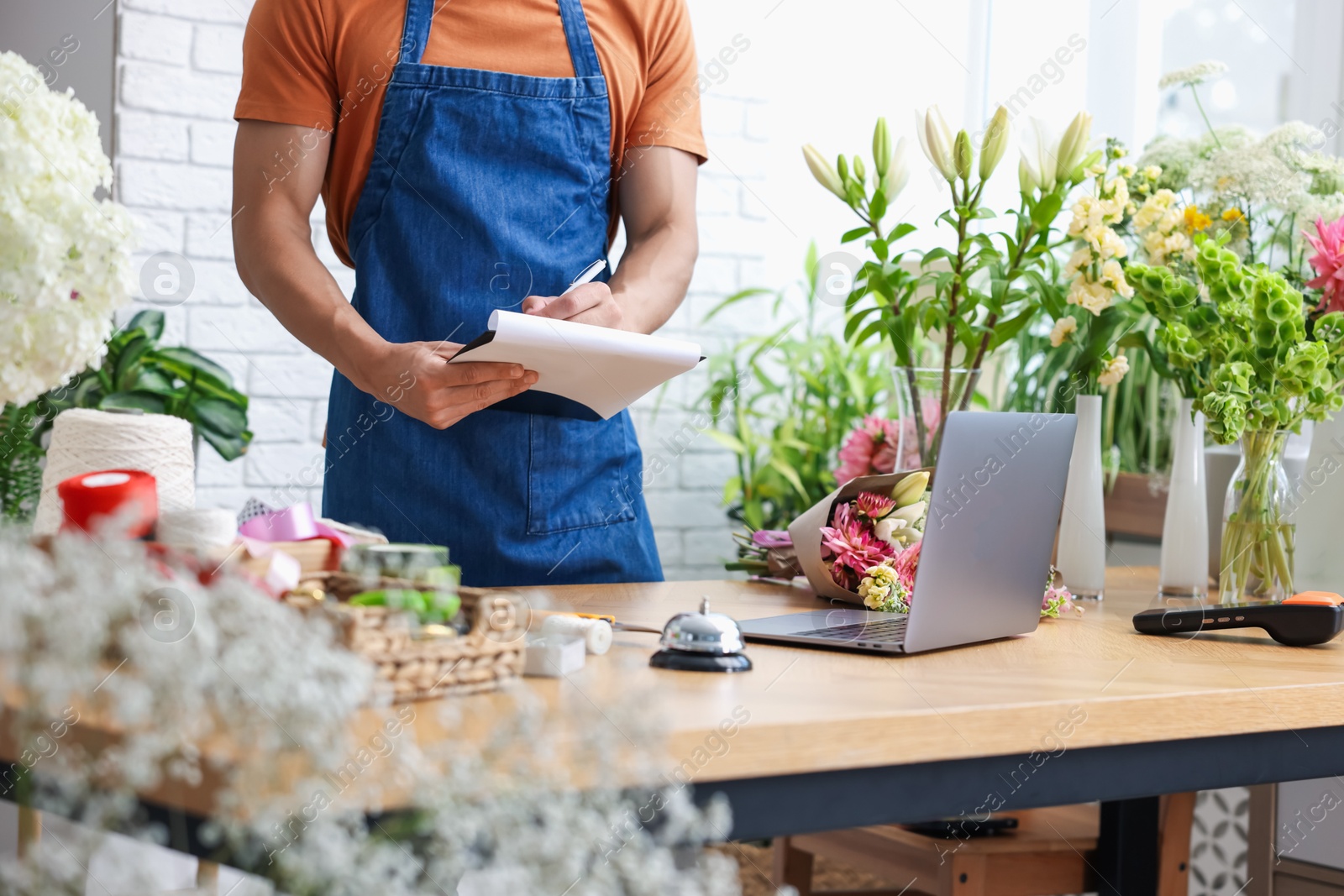 Photo of Professional florist working at wooden table in shop, closeup