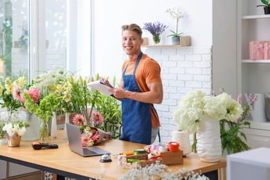Photo of Professional florist working at wooden table in shop