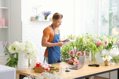 Photo of Professional florist working at wooden table in shop