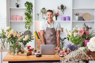 Photo of Professional florist with laptop working at wooden table in shop