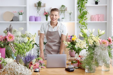 Photo of Professional florist with laptop working at wooden table in shop
