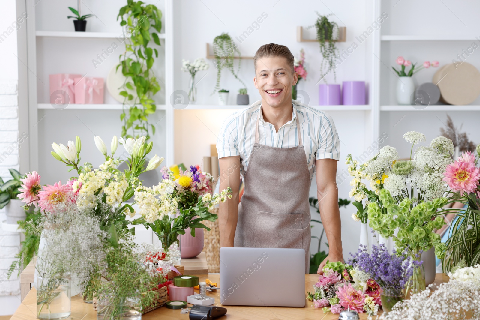 Photo of Professional florist with laptop working at wooden table in shop