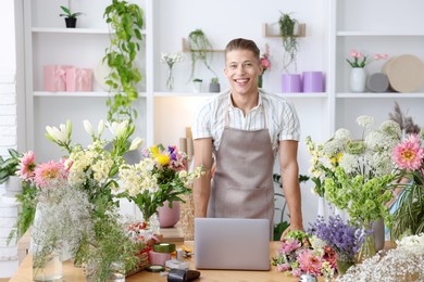 Photo of Professional florist with laptop working at wooden table in shop
