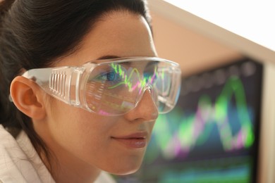 Photo of Young woman wearing glasses with reflection on blurred background, closeup