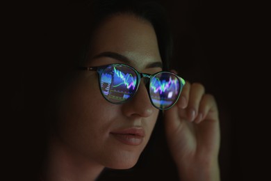 Photo of Young woman wearing glasses with reflection on dark background, closeup