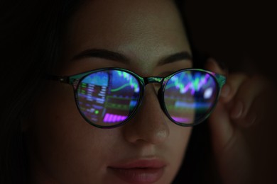 Photo of Young woman wearing glasses with reflection on dark background, closeup