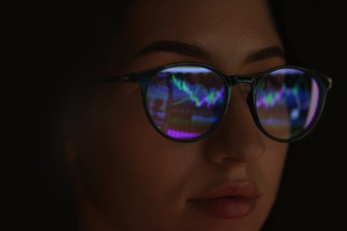 Photo of Young woman wearing glasses with reflection on dark background, closeup