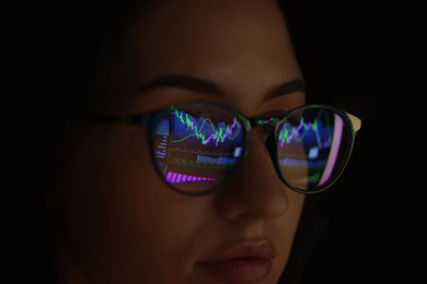 Photo of Young woman wearing glasses with reflection on dark background, closeup