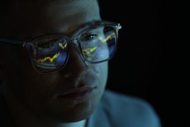 Photo of Young man wearing glasses with reflection on dark background, closeup